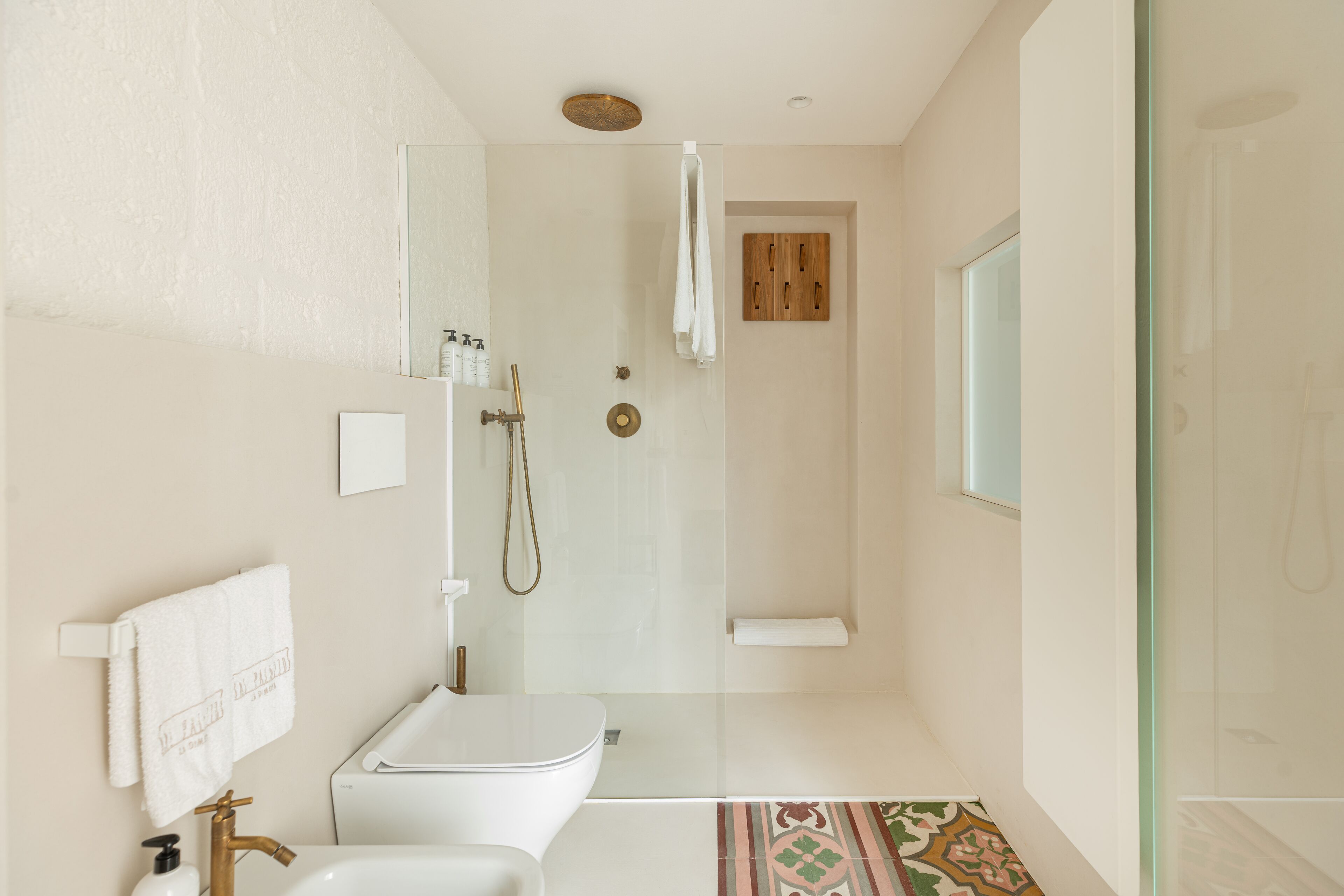 Een moderne badkamer met een douchecabine van glas, een witte wastafel en een toilet.