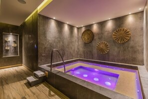 Relax in a serene spa room with a hot tub and decorative wall art.