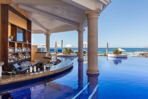 Relax by the infinity pool surrounded by a shaded seating area and a fully stocked bar.