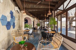 A restaurant with wicker chairs, round tables, and hanging pendant lights. - Experience the Ultimate in Comfort & Convenience: 3BR Condo with Pool (Cabo San Lucas)