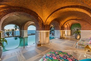 Relax by the large pool overlooking the sea, surrounded by comfortable seating areas and lush greenery.