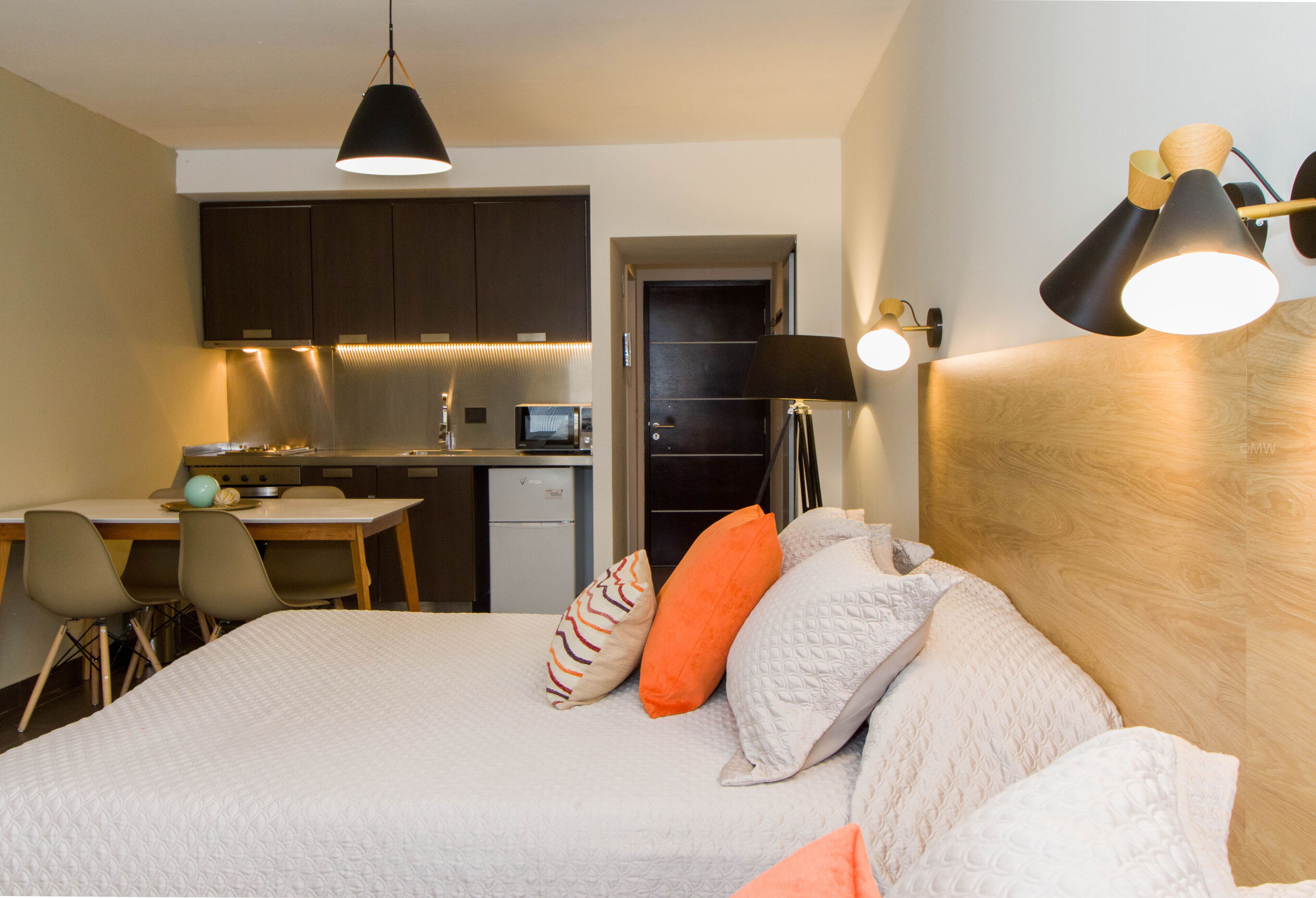 Una habitación de hotel con cama, escritorio y kitchenette.
