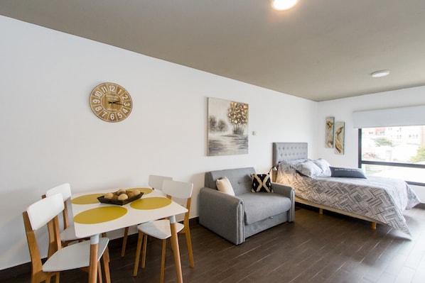 Une pièce moderne et bien éclairée, comprenant une table à manger, des chaises, un canapé et un lit.