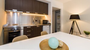 A modern kitchen with stainless steel appliances, a dining table with a decorative bowl, and a floor lamp.