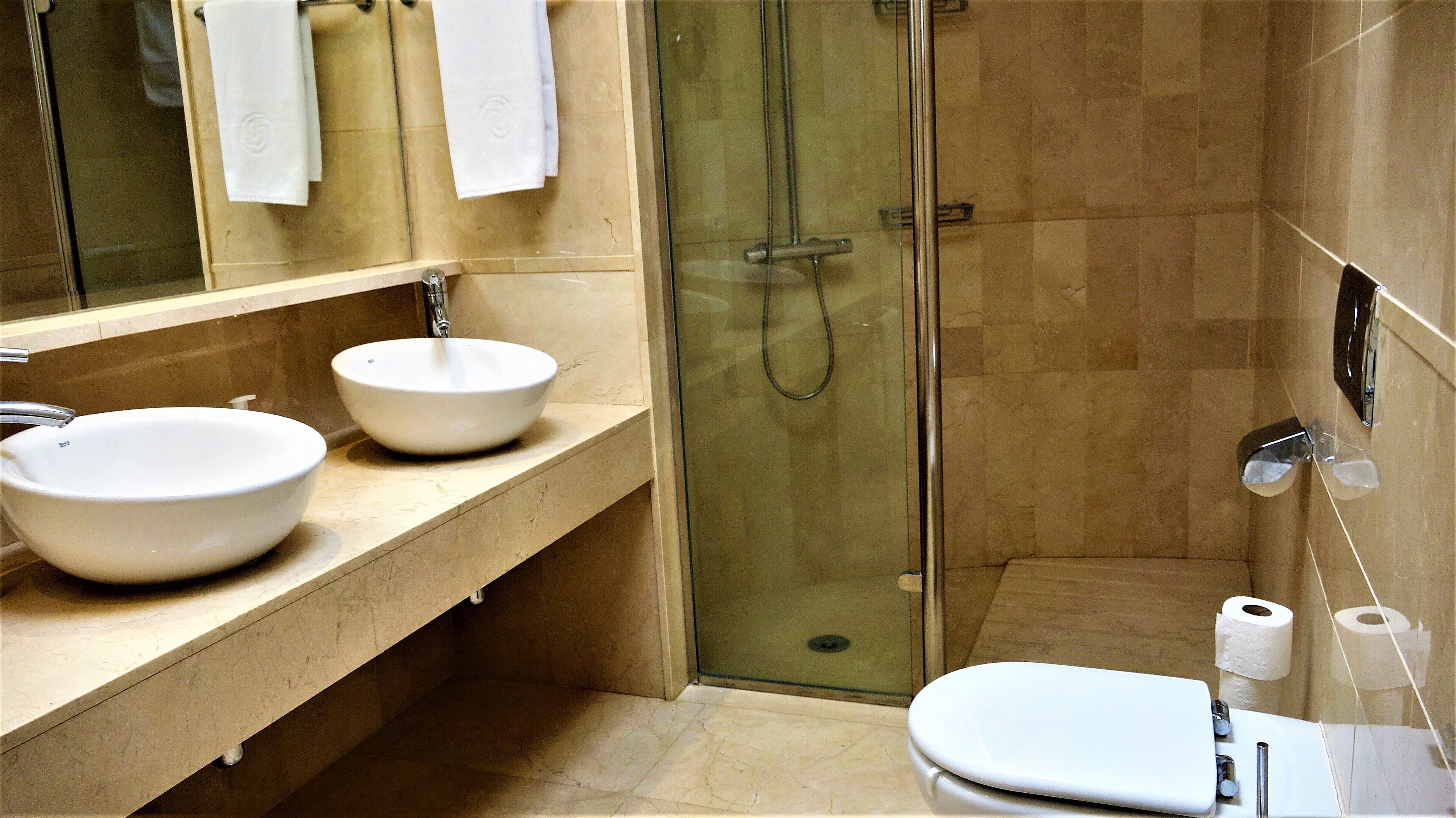 A bathroom with two sinks, a toilet, a shower, and a mirror.