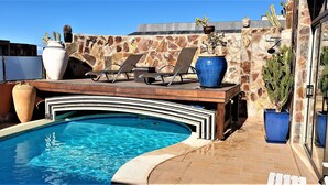 A pool area with a stone wall, lounge chairs, and potted plants. - 5 stars super luxury villa (TAURO MOGAN)