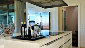 A modern kitchen with a stainless steel refrigerator, a glass coffee table, and a basket of wooden sticks. - 5 stars super luxury villa (TAURO MOGAN)
