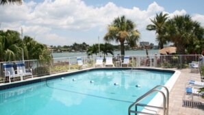 A swimming pool with lounge chairs and a view of the water. - Westwinds Waterfront Luxury Condo Beach and Pool (Treasure Island)