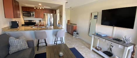 Una sala de estar moderna con un sofá gris, una mesa de centro de madera y un televisor montado en la pared.