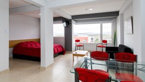 A modern hotel room with a bed, a desk, and two chairs.