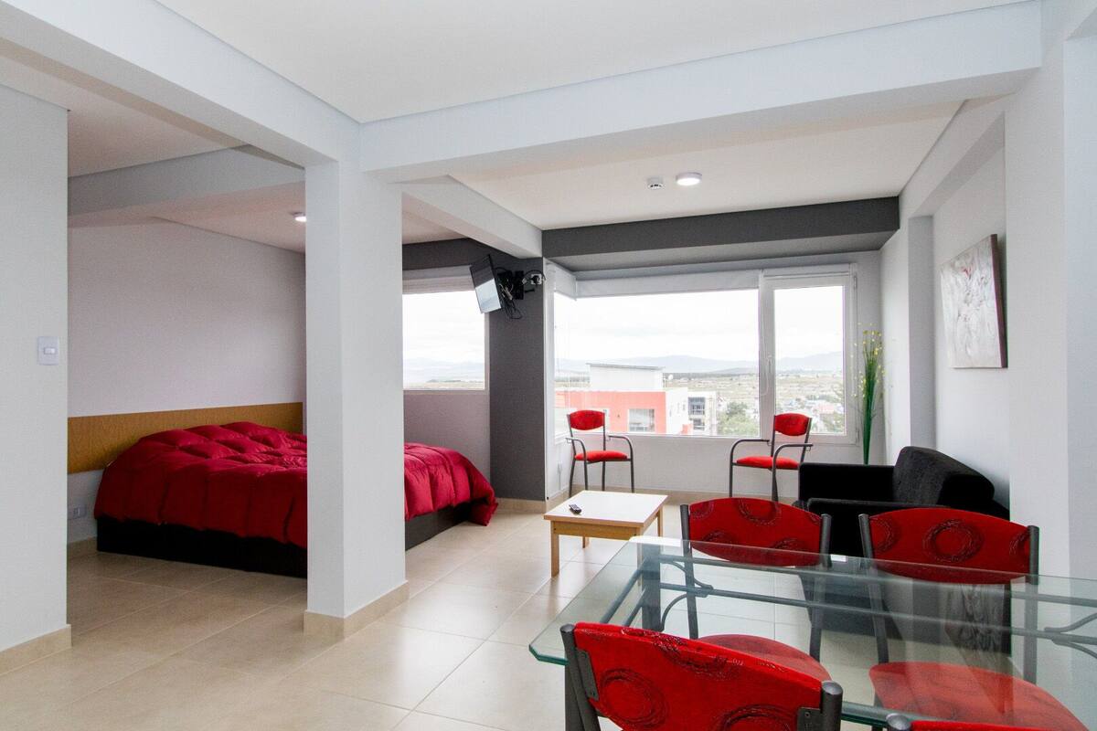 A modern hotel room with a bed, a desk, and two chairs.