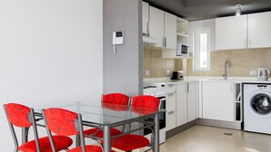 A modern kitchen with white cabinets, a microwave, a stove, and a washing machine.