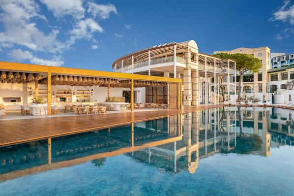 A modern hotel with a pool, outdoor seating, and a covered area.