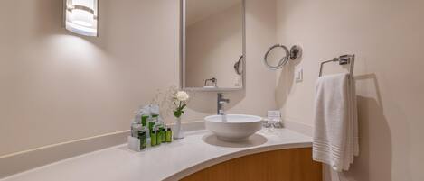 A modern bathroom with a white sink, a large mirror, and a towel rack.