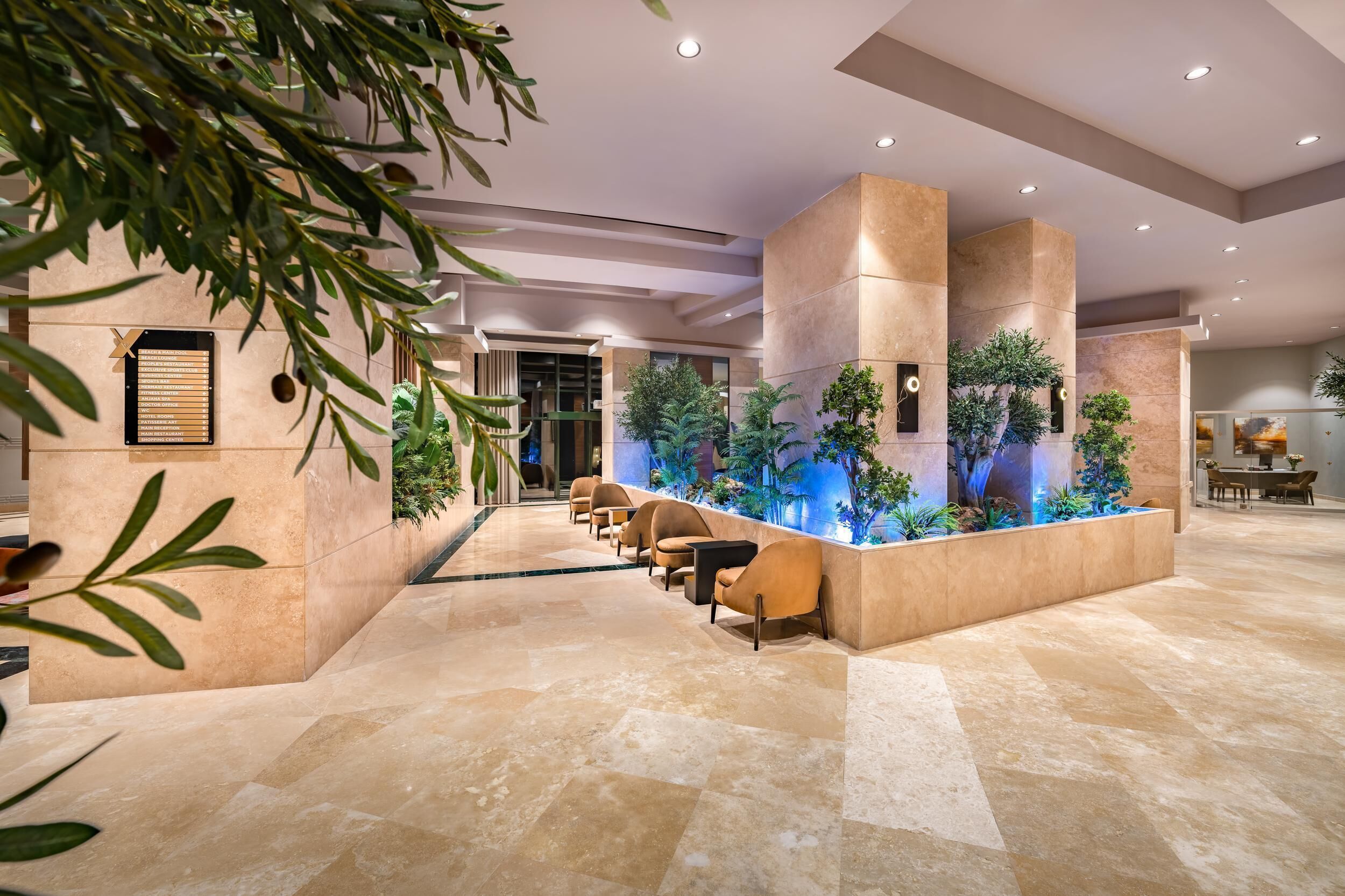 A modern lobby with a reception desk, seating area, and indoor plants.
