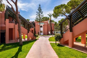 A modern building with a central courtyard, surrounded by trees and a clear sky.