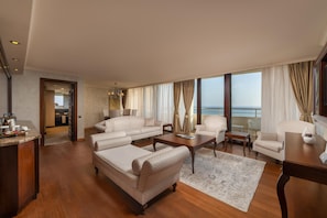 A spacious living room with a large window, a sofa set, a coffee table, and a view of the sea.