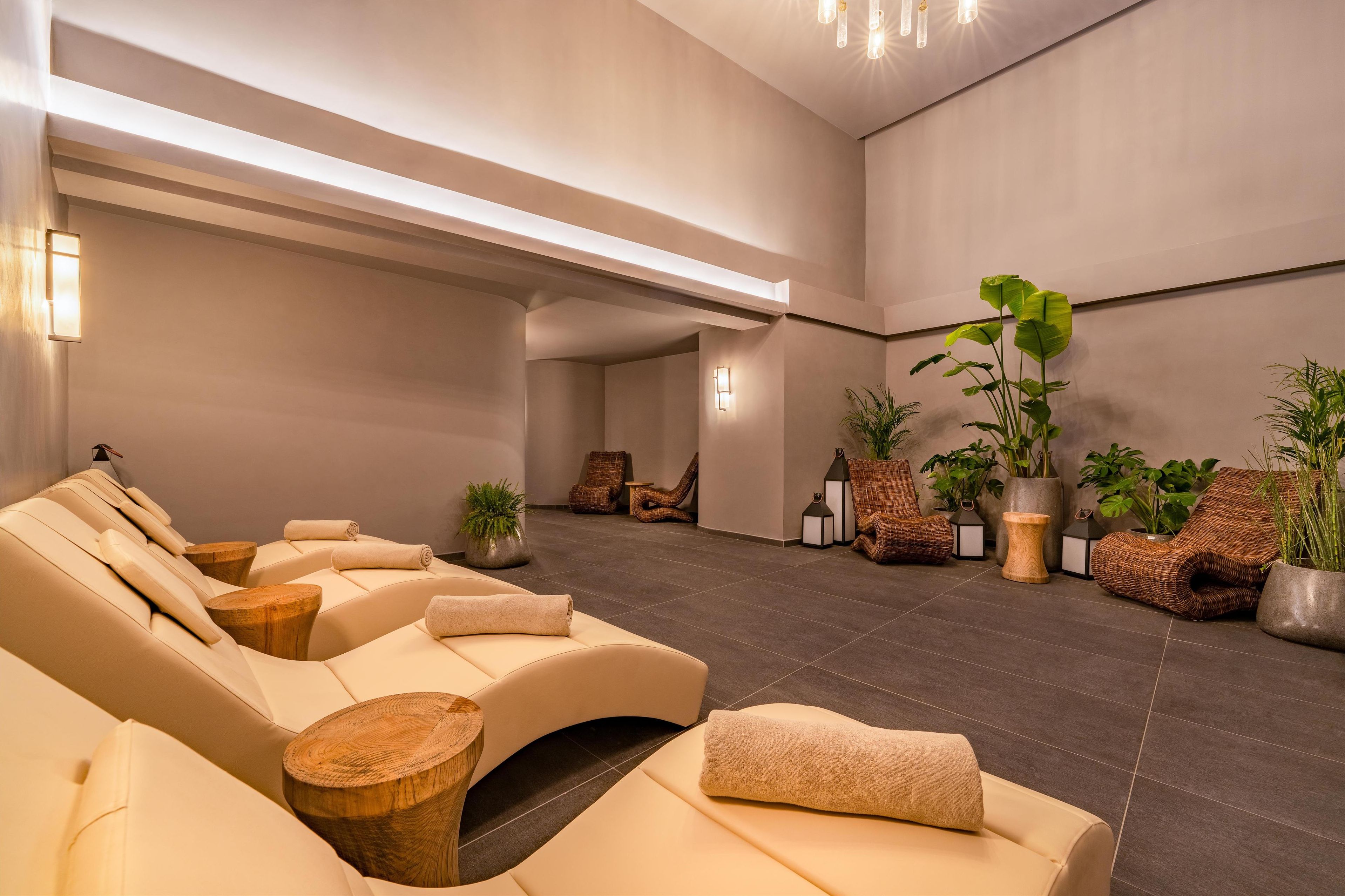 A spa area with reclining chairs, wooden side tables, and potted plants.