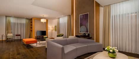 A modern living room with a grey sectional sofa, a round coffee table, and a TV.