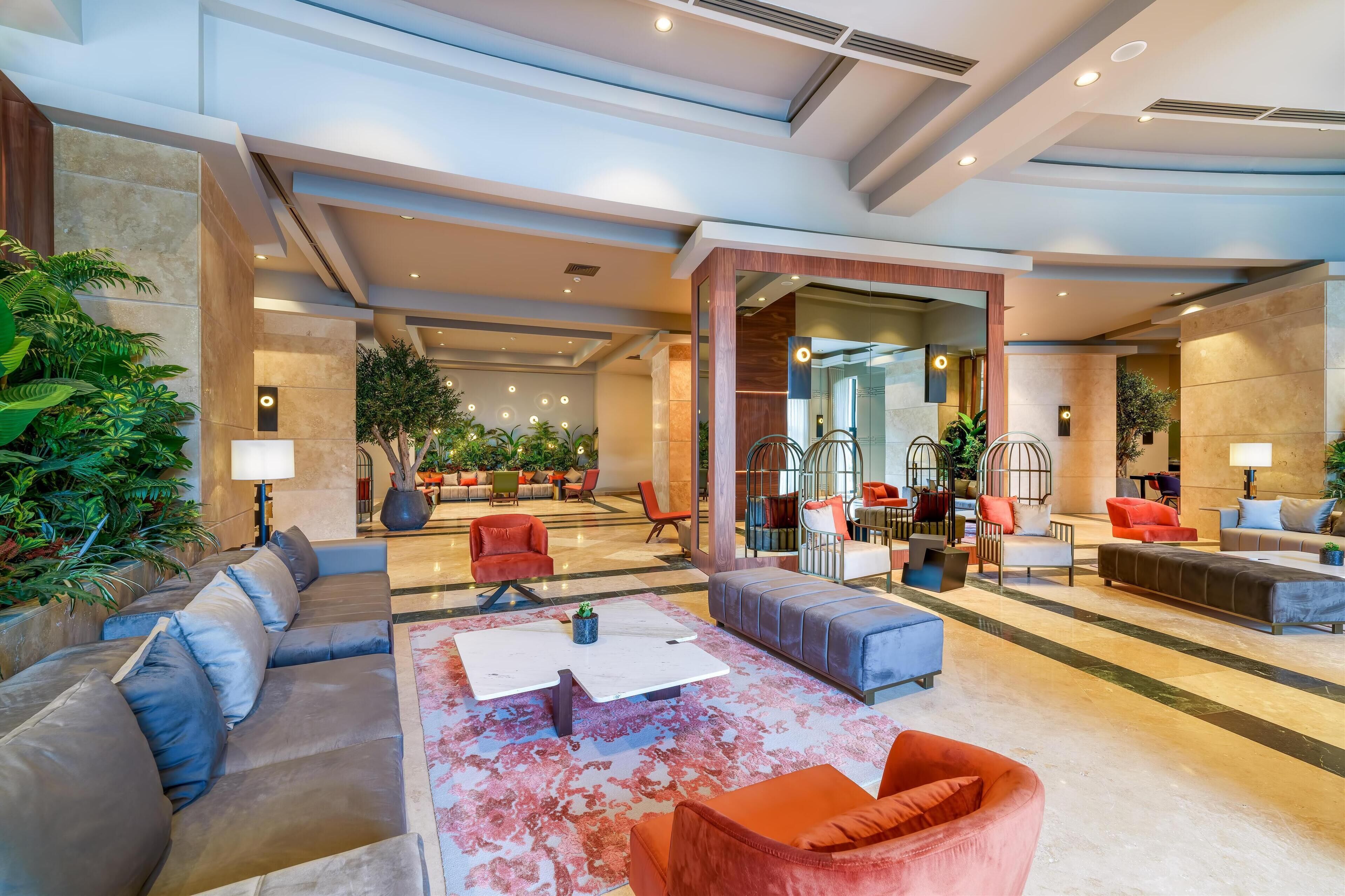 A spacious lobby with modern seating, a central coffee table, and a large mirror.