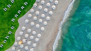 An aerial view of a beach with rows of umbrellas and lounge chairs, a clear view of the ocean, and a grassy area. - Rixos Park Belek - All Inclusive - The Land of Legends Access (Serik)