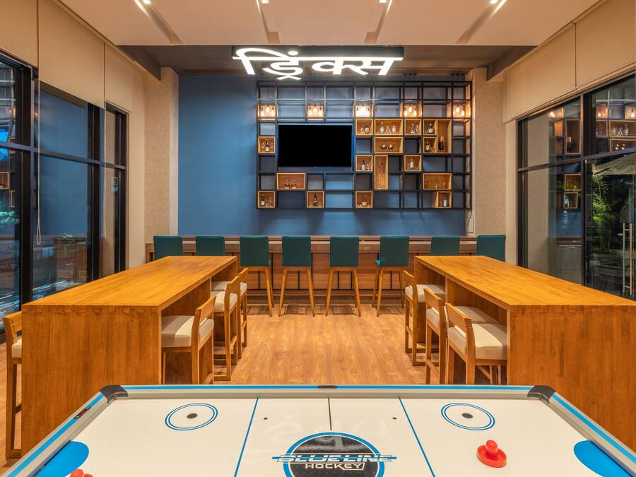 Zona de bar moderna con mesa de billar, taburetes y estanterías llenas de botellas.