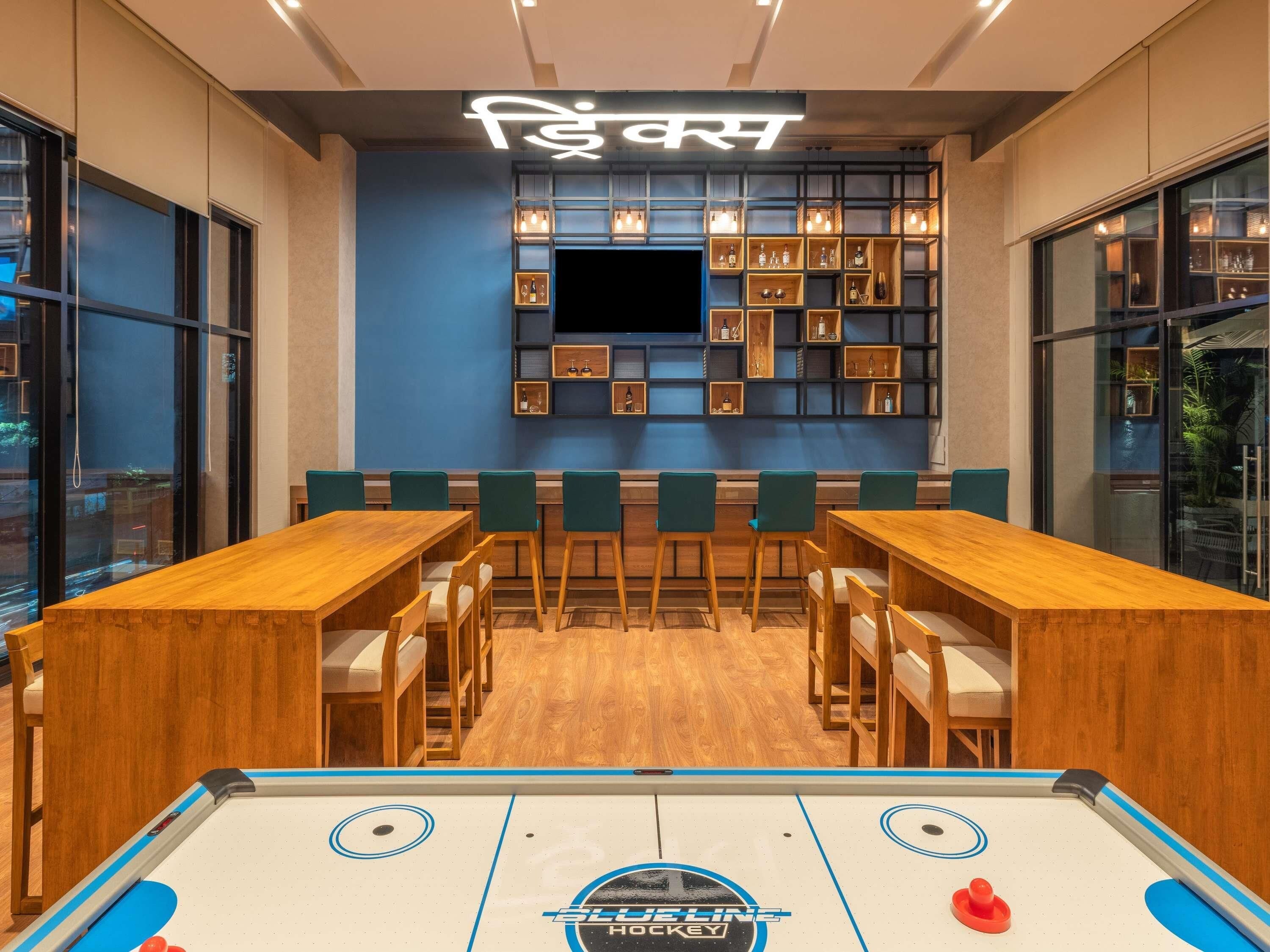 Une pièce équipée d’une table de billard, d’un bar et de coins salon.