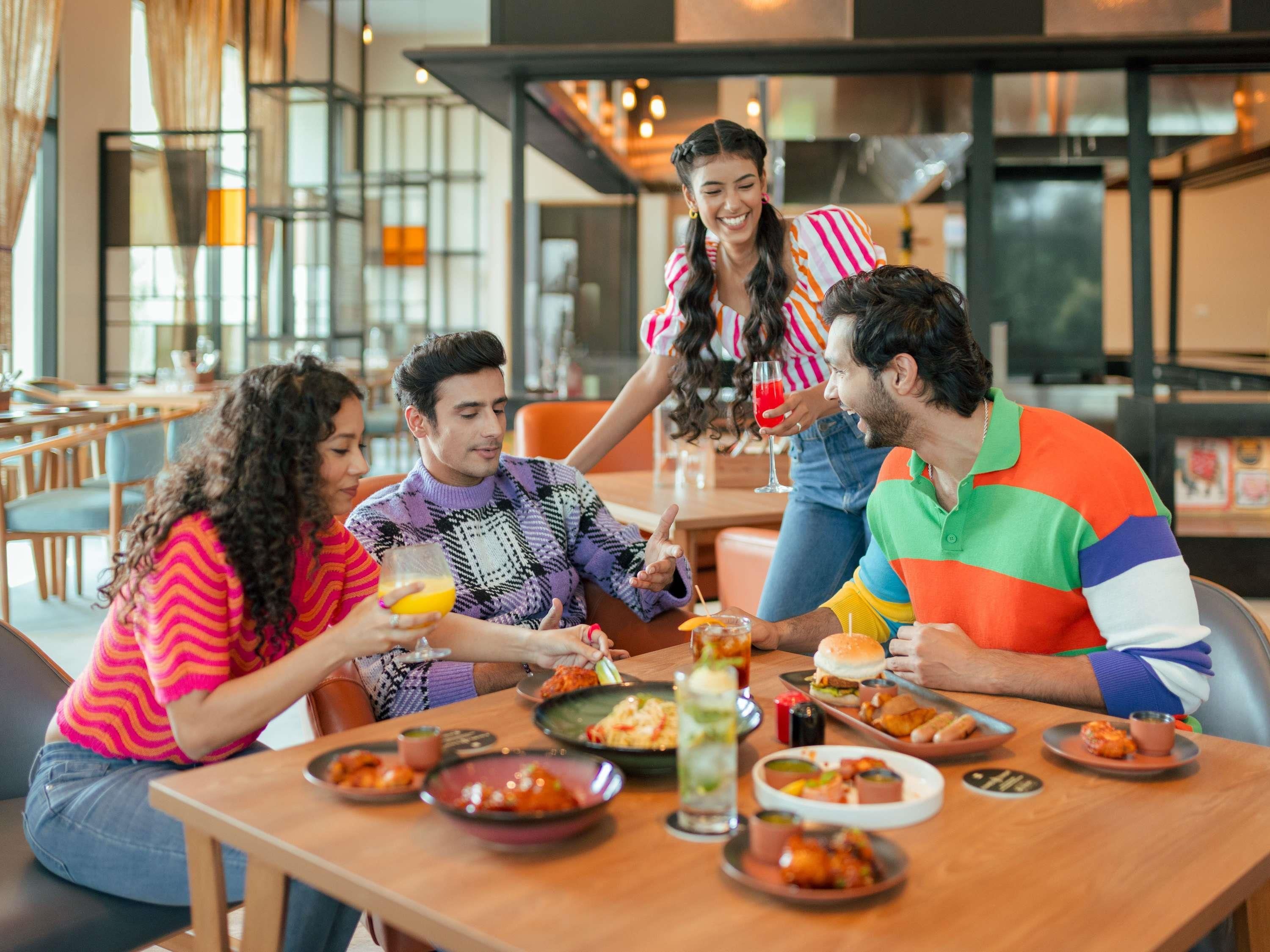 A group of people dining at a restaurant with various dishes and drinks on the table.