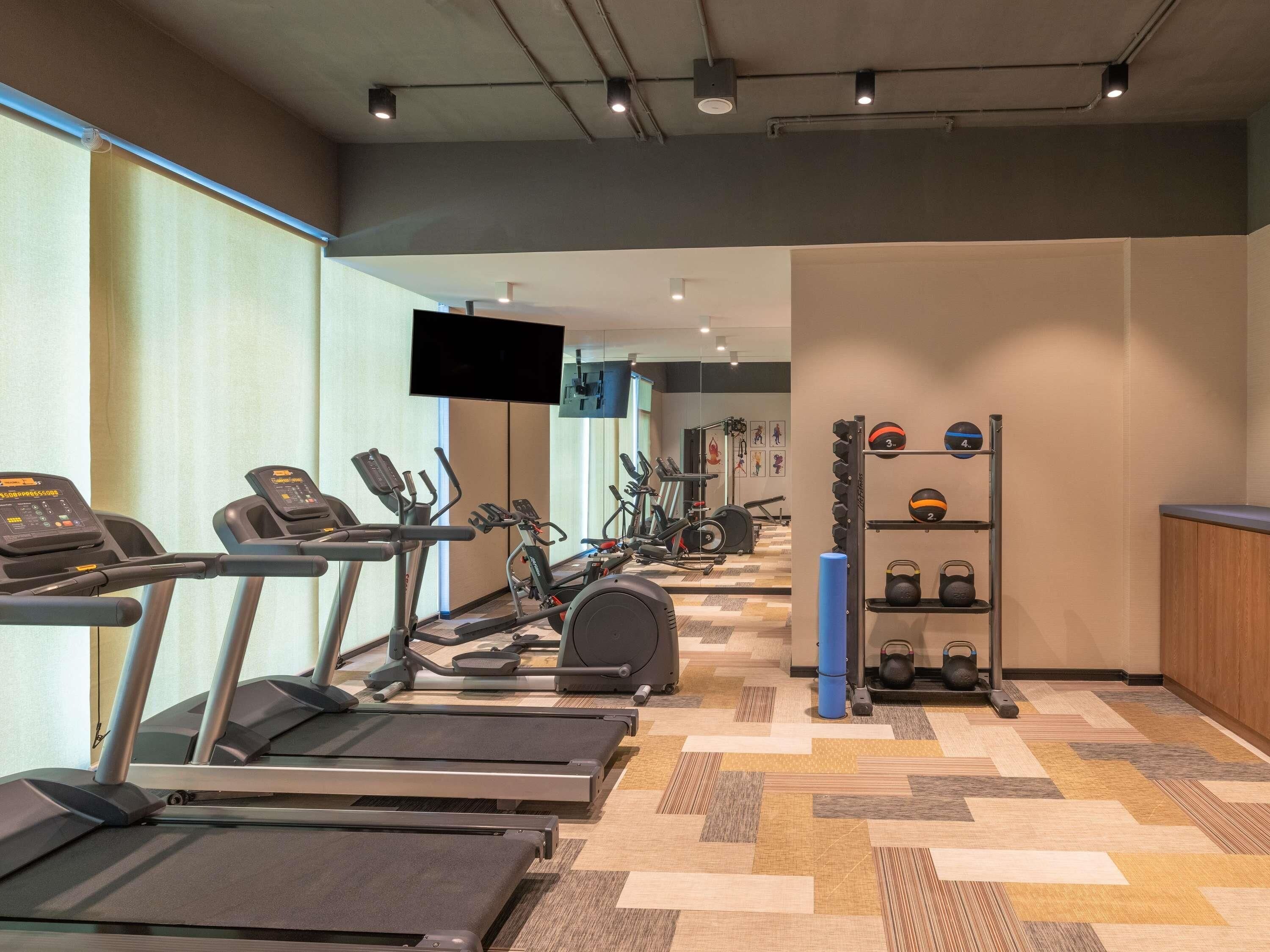 A gym with treadmills, elliptical machines, and weightlifting equipment.