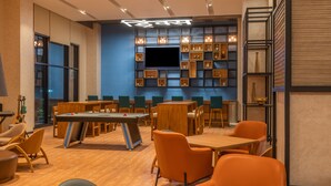 A modern lounge area with a pool table, multiple seating arrangements, and a wall-mounted television. - Ibis Thane (Thane)