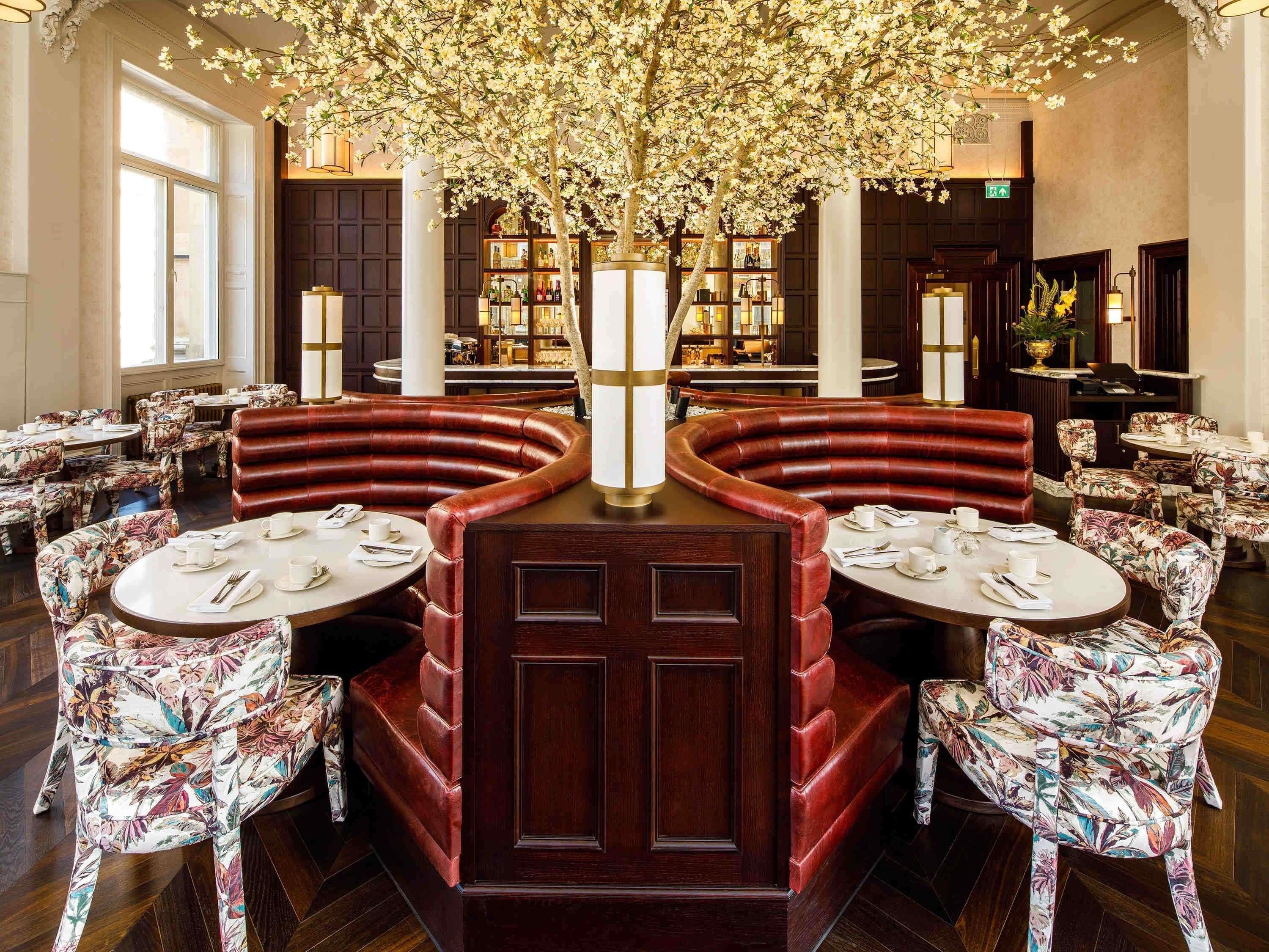 A restaurant with round tables, red cushioned booths, and a central floral arrangement.