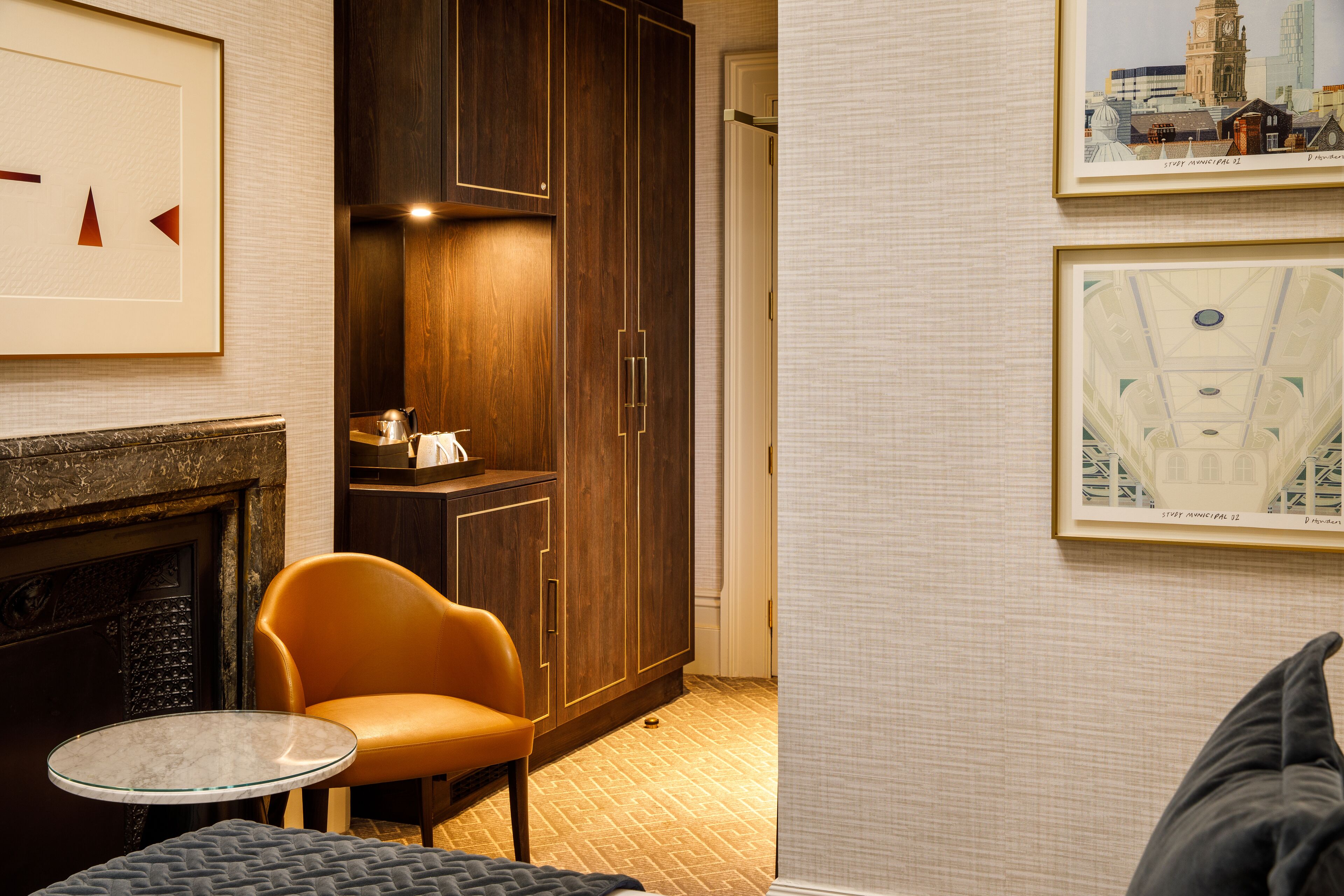 A hotel room with a fireplace, a round table, a sofa, and a large wardrobe.