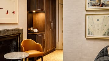 A hotel room with a fireplace, a round table, a sofa, and a large wardrobe.