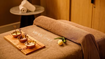 Un cuarto de spa con un armario de madera, una pequeña mesa redonda con una toalla y una bandeja de madera con cuencos y una ramita de lavanda.
