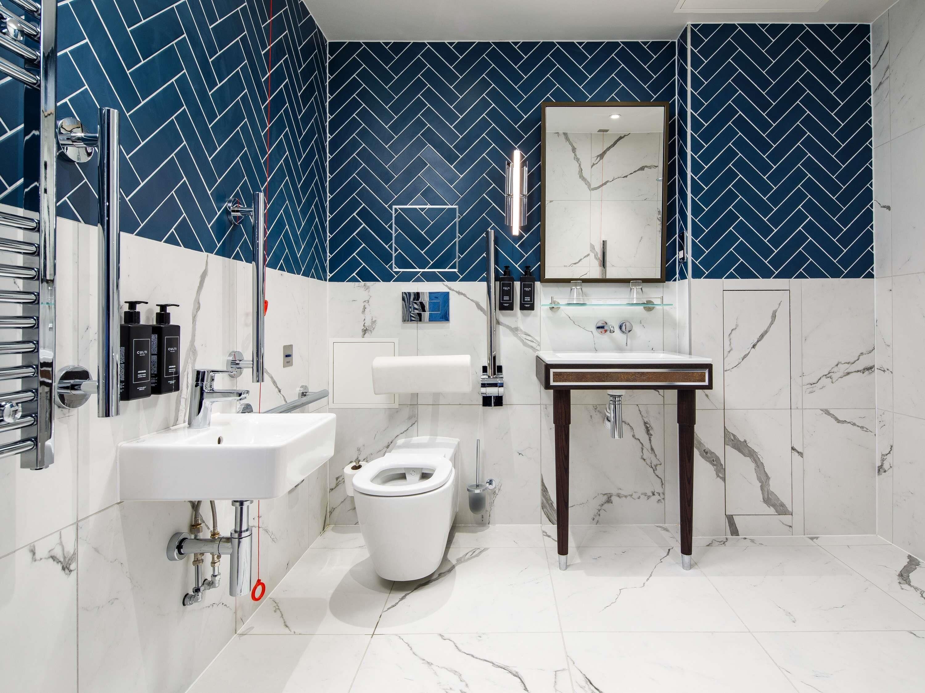 A modern bathroom with a white marble sink, a toilet, and a mirror above the sink.