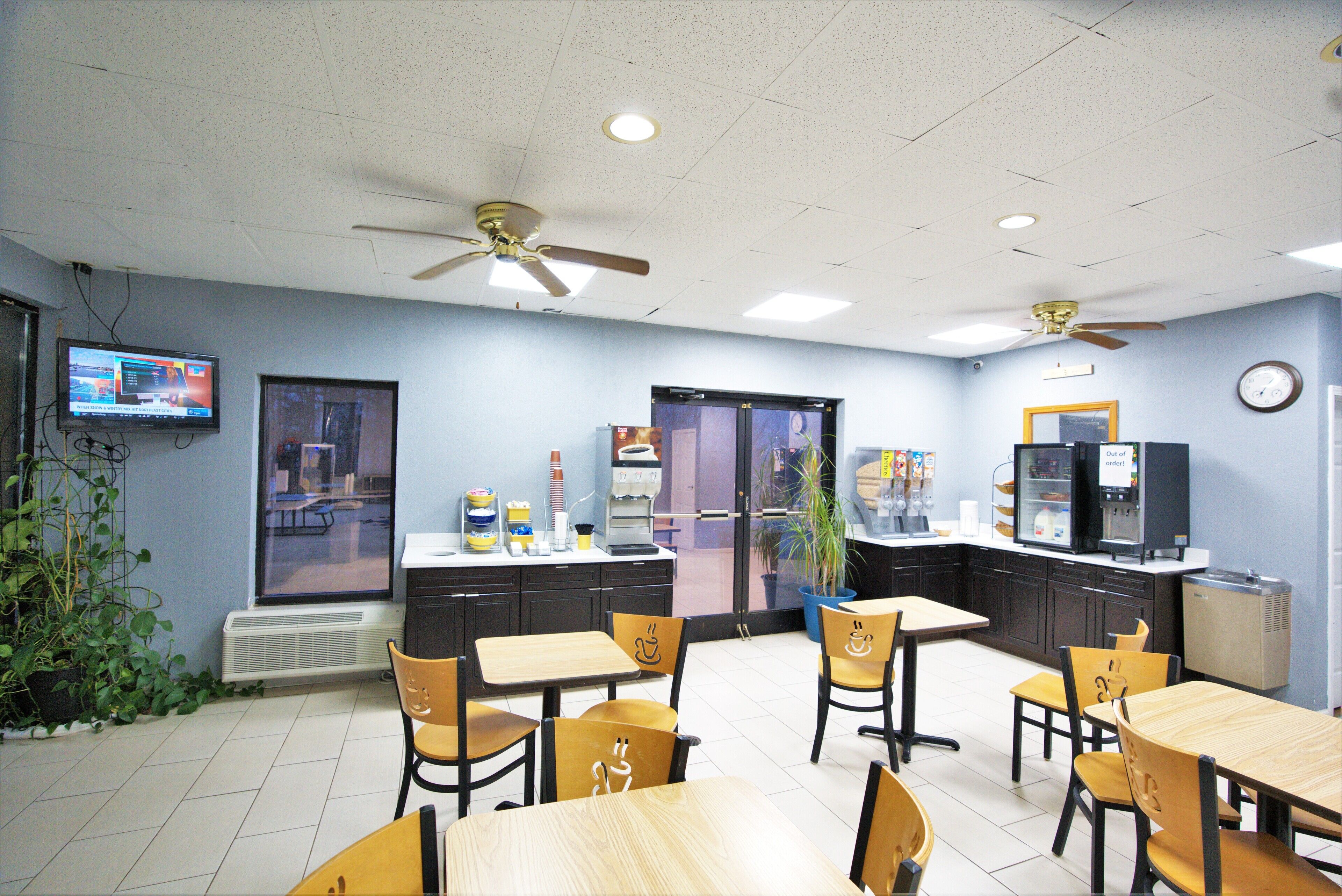 A dining area with tables and chairs, ceiling fans, a television, and a vending machine.