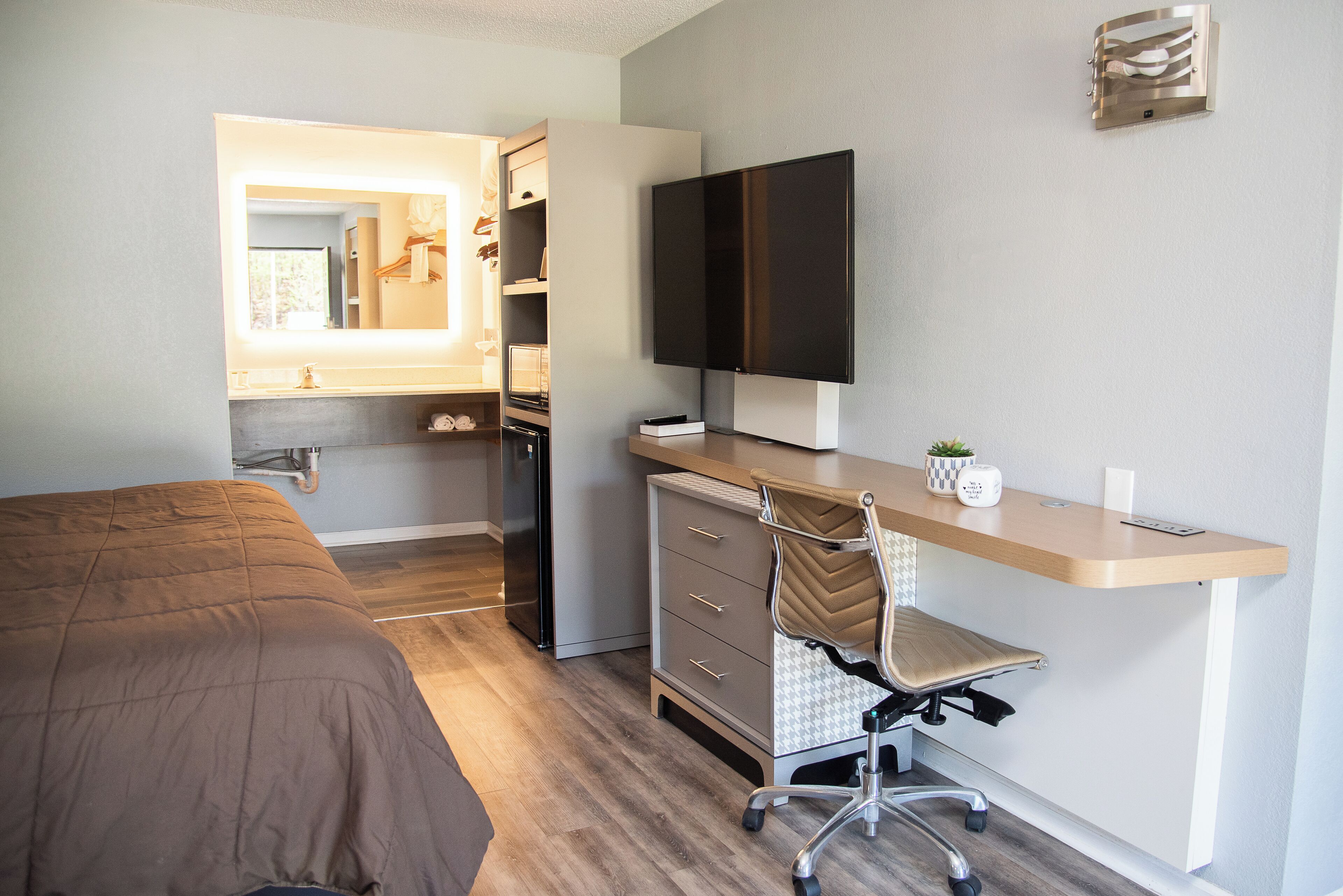 A bedroom with a bed, a desk with a chair, a television, and a wardrobe.