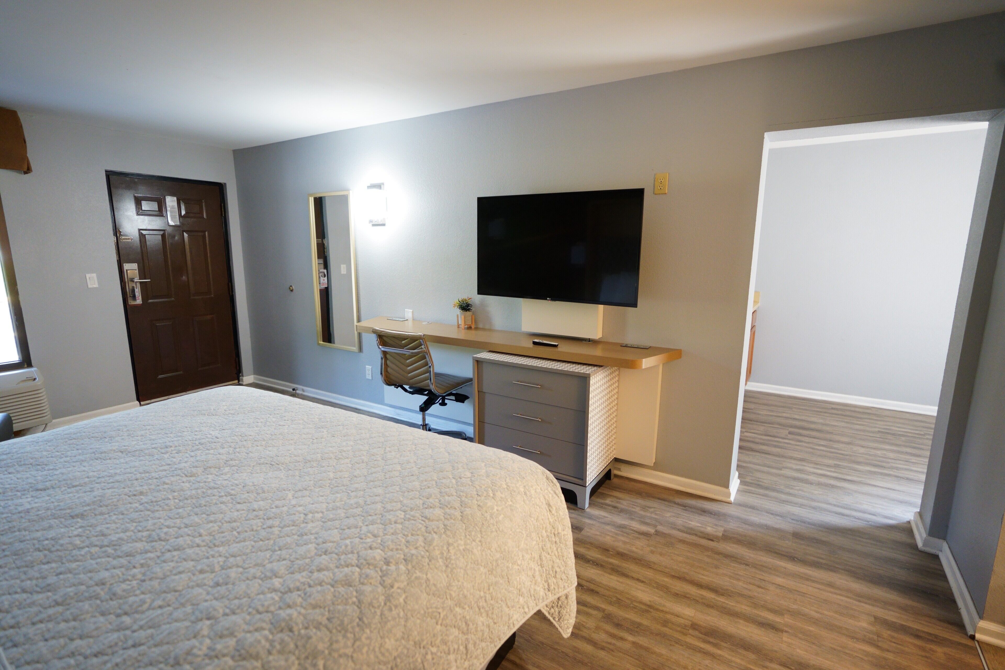 Une chambre dotée d’un grand lit, d’un bureau avec un téléviseur à écran plat, d’une chaise et d’une armoire.