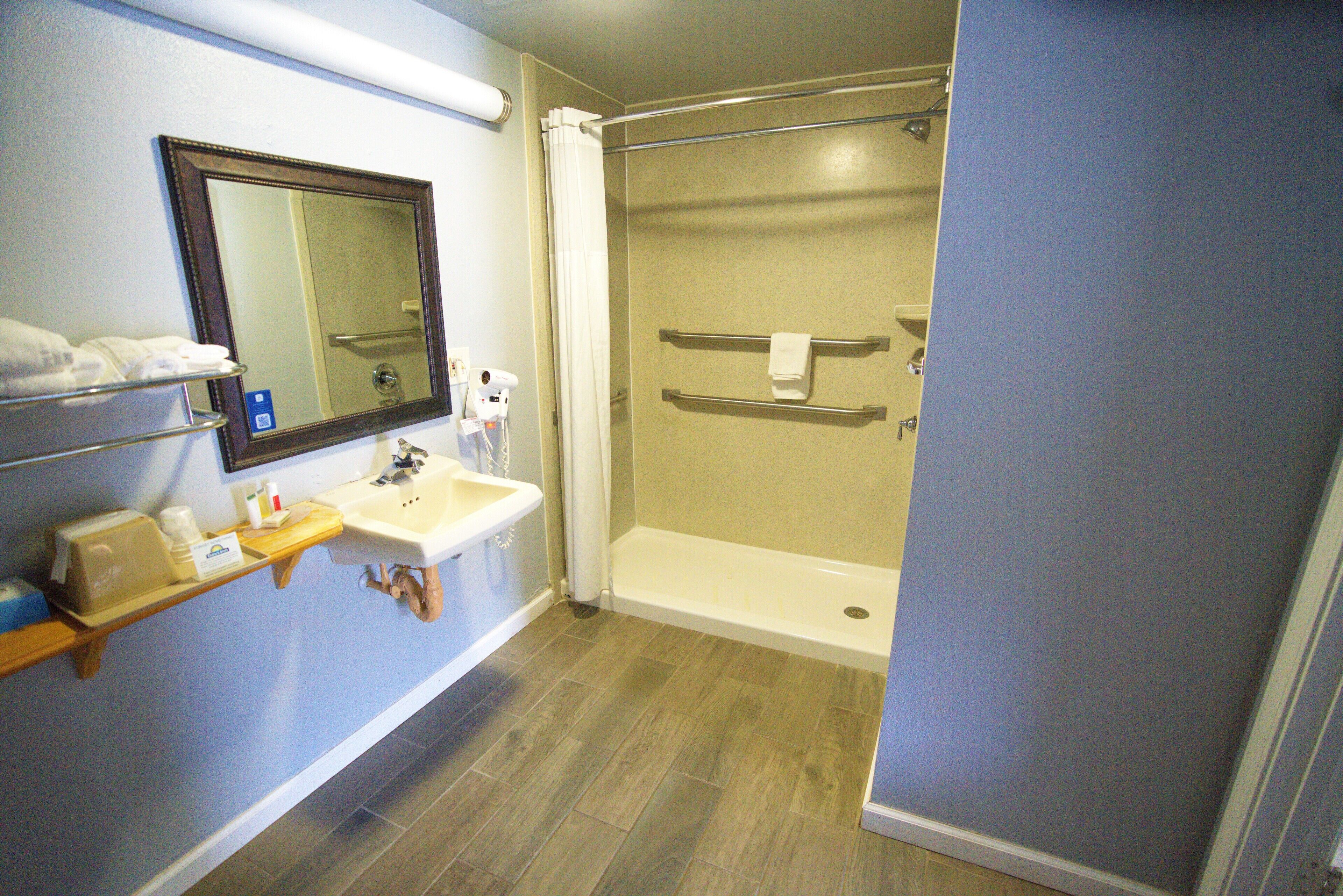 A bathroom with a shower, sink, and mirror.