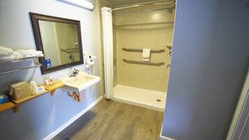 A bathroom with a shower, sink, and mirror.