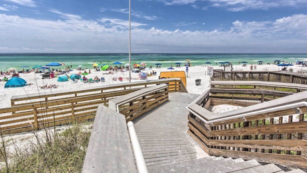 Ein Strand mit Holzstegen, Zelten und Sonnenschirmen.