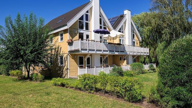 A two-story house with a balcony, surrounded by greenery. - FeWo „Skipper“ 71m², 4 Pers. im Marinapark Scharmützelsee, Sauna, Whirlpool, Kamin (Wendisch Rietz Siedlung)