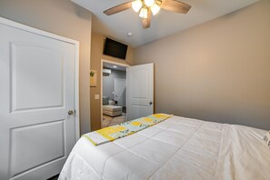 A bedroom with a bed, a ceiling fan, and a door leading to another room.