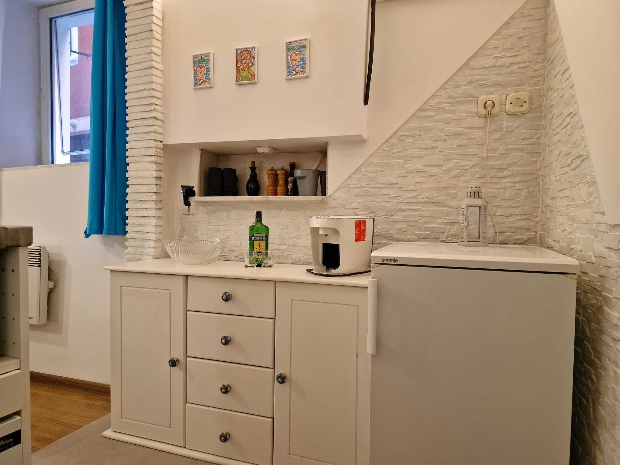 A kitchenette with a microwave, a coffee maker, and a shelf with bottles.