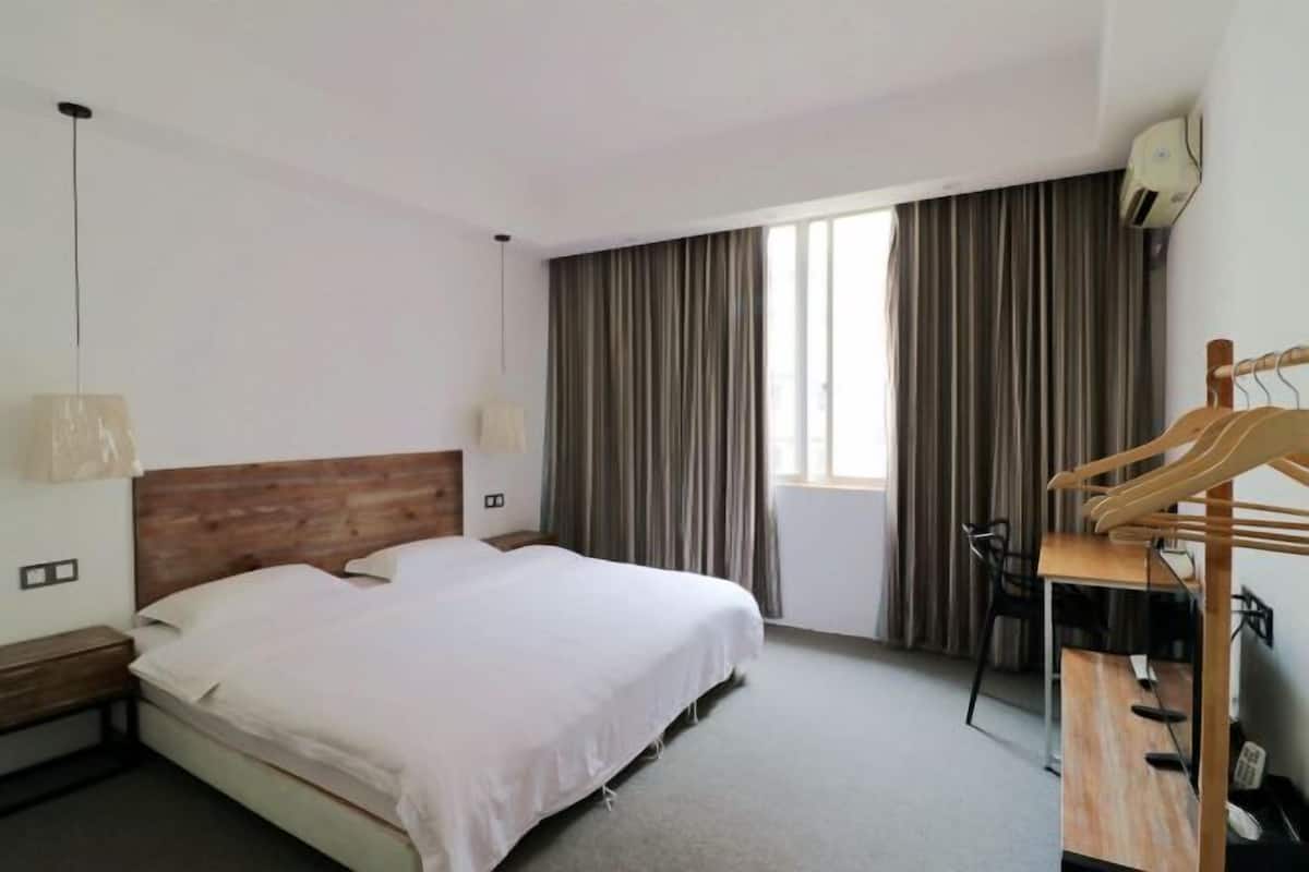 A hotel room with a bed, a desk, a chair, and a window with curtains.