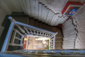 A staircase with a handrail and a door at the bottom leading to a room. - Xiyu Hostel · Cat Café (Yangshuo)