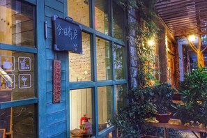 A building with a blue facade, a signboard, and potted plants. - Xiyu Hostel · Cat Café (Yangshuo)