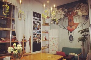 A dining area with a wooden table, chairs, and a mural on the wall. - Xiyu Hostel · Cat Café (Yangshuo)