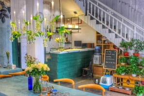 A restaurant with a bar area, seating, and a staircase. - Xiyu Hostel · Cat Café (Yangshuo)