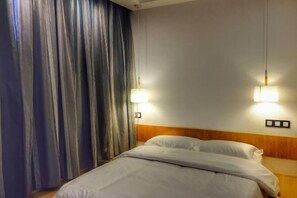 Una habitación de hotel con una cama, dos luces fijadas a la pared y una cortina.
